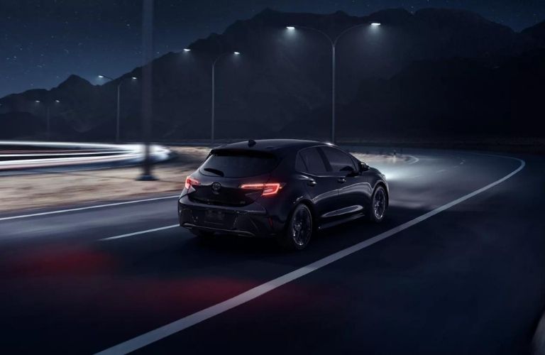 A 2022 Corolla Hatchback on a well-lit road at night